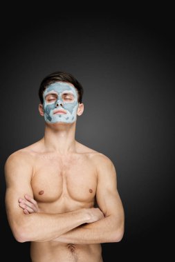 Bir yüz çamur kil maskesi, yüz ve vücut cilt bakım tedavisi ile güzel bir genç adam portresi.