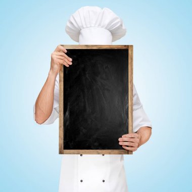 Restoran şefi, bir iş yemeği menüsü için boş bir karatahtanın arkasına saklanıyor..