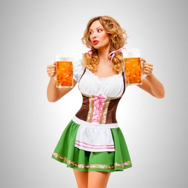 Bira bardağı gri arka plan üzerinde hizmet veren bir geleneksel Bavyera elbise dirndl giyen güzel Oktoberfest kadın.