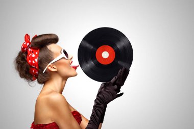 Güzel pinup bikini modeli, LP microgroove vinil kaydı gri arka plan üzerinde yalama.