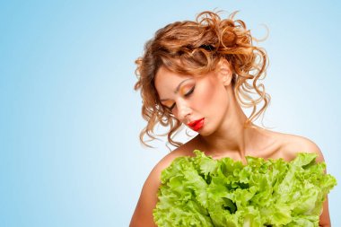 Marul, mavi arka plan üzerinde bir eko-yeşil elbise gibi görünenleri yaratıcı yeşil saklanıyor diyet güzel bir üstsüz kız portresi bırakır.