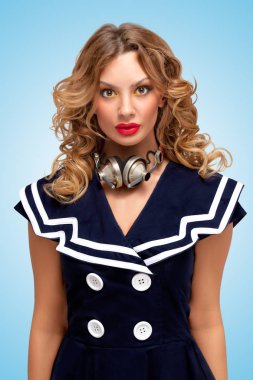 Retro vintage müzik kulaklık mavi zemin üzerine onun boynuna bir moda pin-up denizci kız fotoğrafı.