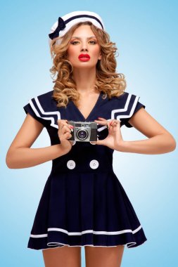 Mavi arka plan üzerinde poz eski bir vintage fotoğraf kamera ile fotoğraf çekme bir göz alıcı pin-up denizci kız Retro fotoğraf.