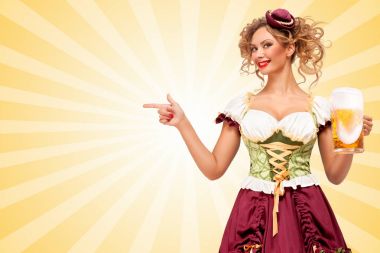 Güzel gülümseyen seksi Oktoberfest garson geleneksel Bavyera giyiyor elbise bira bardağı tutan ve bir kenara renkli karikatür tarzı arka plan üzerinde işaret dirndl.