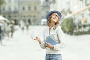 Mutlu genç öğrenci kitap okuma ve Kentsel şehir arka planı eğitim için holding ile bir kahve-to-go,.