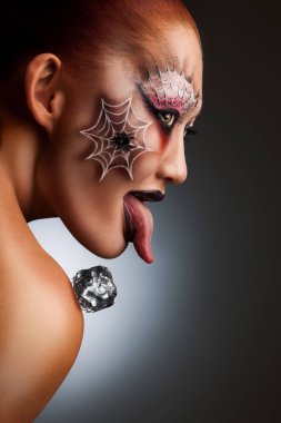 halloween örümcek dövmeli bir kız portresi yüzündeki korku maske olarak omzuna buz küpü ile boyalı.