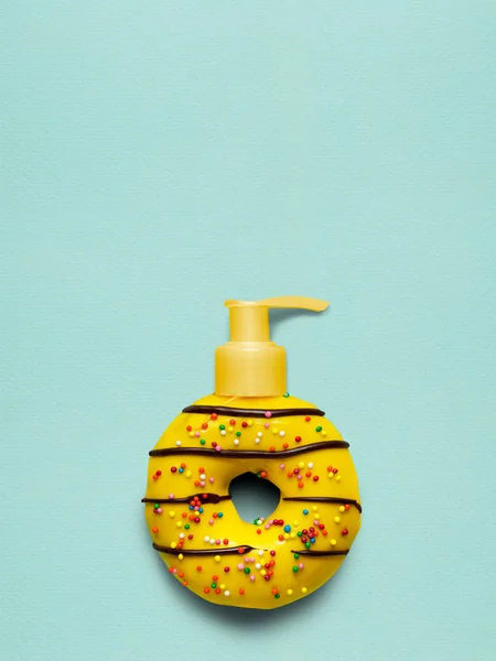 美味甜黄甜甜圈与化妆品泵机在蓝色背景上的创意静物写生 — 图库照片