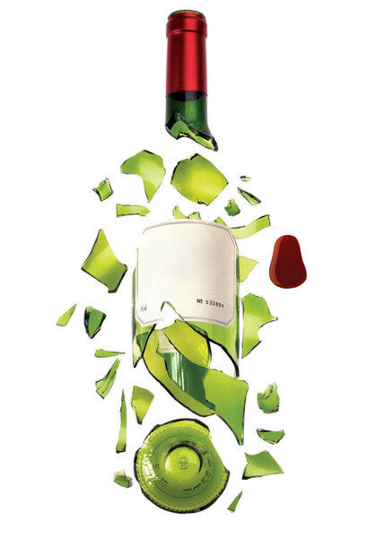 A bottle of wine made of green transparent glass with label and red top broken into pieces.