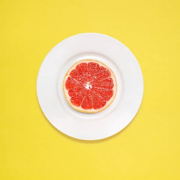 Красный Грейпфрутовый Ломтик Белой Тарелке Желтом Фоне — стоковое фото