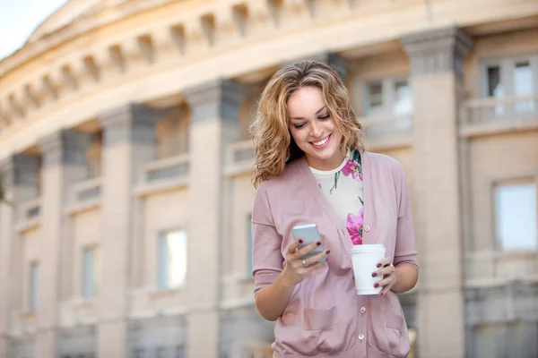 携帯電話の電子メールをチェックして取るに離れてコーヒーのカップを保持している美しい女性 — ストック写真