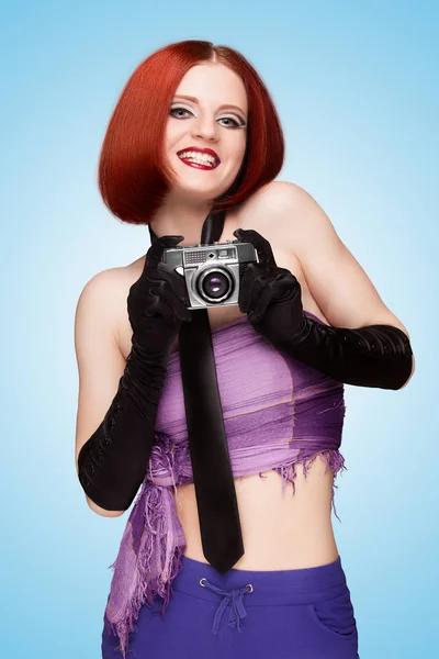 魅力四射的快乐的女孩 穿着一条领带和长手套 用旧老式照片相机拍照 说在蓝色背景上的奶酪 — 图库照片