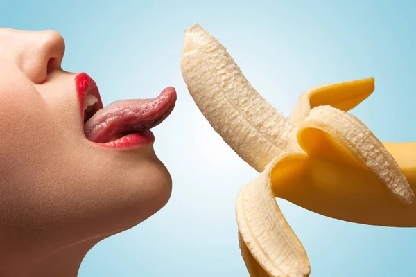 一脸的一个性感的女孩 正在舔着一根半剥的黄香蕉 — 图库照片