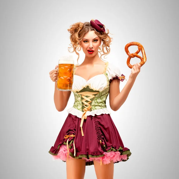 美丽的慕尼黑啤酒节服务员穿着巴伐利亚传统服饰裙抱着椒盐脆饼和啤酒的杯子 在灰色的背景上 — 图库照片