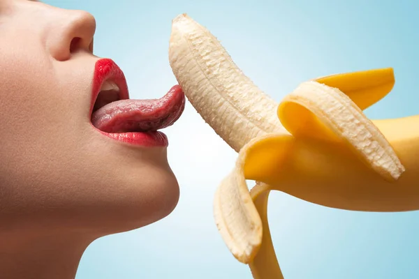 一脸的一个性感的女孩 正在舔着一根半剥的黄香蕉 — 图库照片