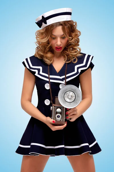 Retro şaşırtıcı eski bir vintage fotoğraf makinesi flaş ampul ile mavi arka plan üzerinde bir moda pin-up denizci kız fotoğrafı.