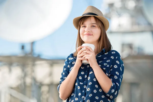 幸せな若い女テイクアウト コーヒーを押しながら放物線パラボラ アンテナ衛星からの無線信号を受け取るの背景とポーズ — ストック写真