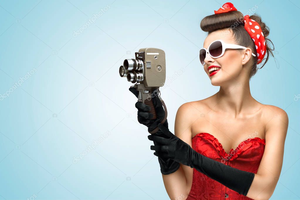 A photo of the pin-up girl in corset and gloves holding vintage 8mm camera.