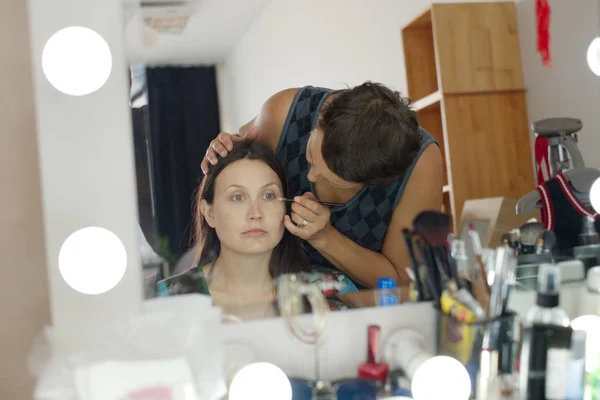 Makyaj sanatçısı, yatay çerçeve. Aynanın önündeki kadına makyaj yapan kadın. — Stok fotoğraf