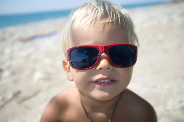 Retrato de menino pequeno em óculos de sol na praia — Fotografia de Stock