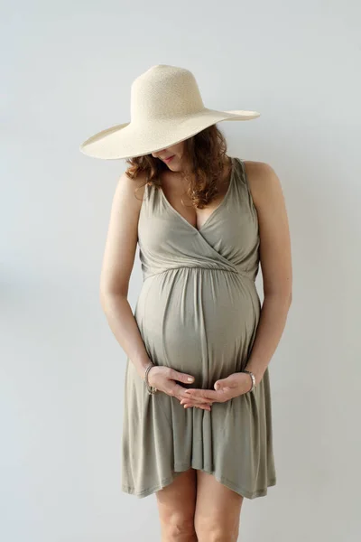 Feche o tiro da mulher grávida impessoal no chapéu que segura a sua grande barriga. À espera do bebé. Maternidade . — Fotografia de Stock