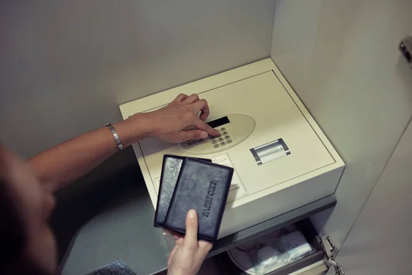 Two hands getting ready to put passports in a safe with digital locker