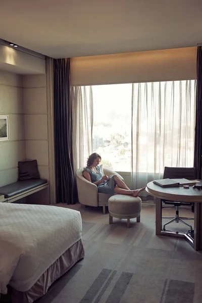 Woman relaxing in the armchair near the window in a hotel room — Stock Photo, Image