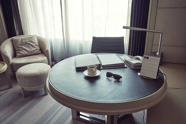 Okrągły, skórzany stół w pokoju hotelowym z dużym oknem na ścianie — Zdjęcie stockowe