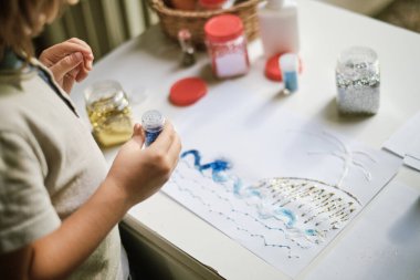 Bir resim yaratmak için parıltı kullanan çocuk. 