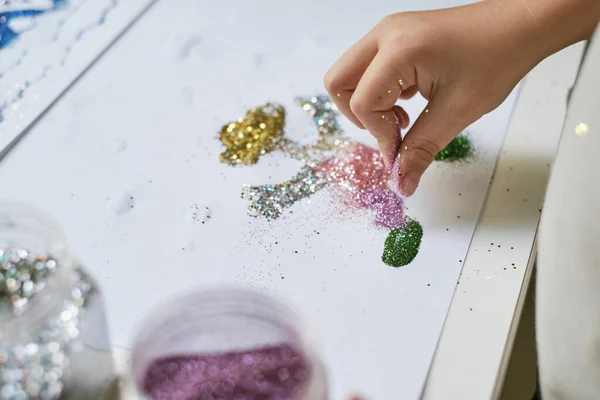 Childs hand making funny art work with glitter. Art lesson for kids. Handcrafting.