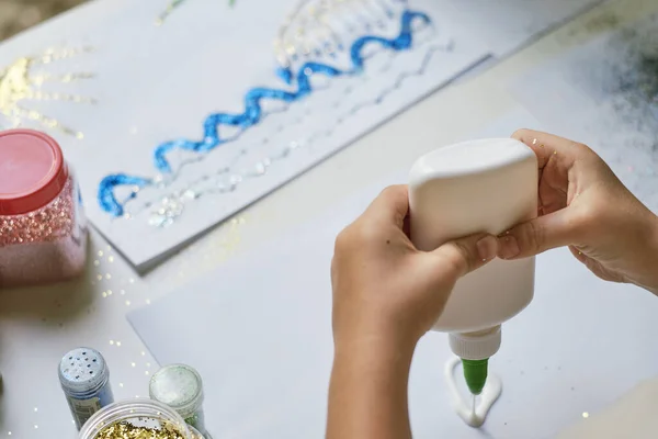 Childs hands applying glue to the paper