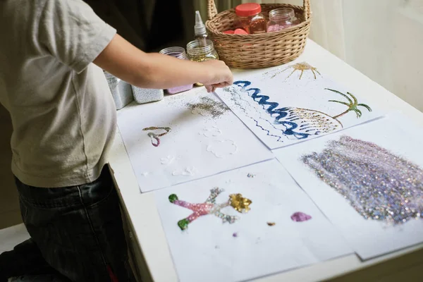 Дитина робить ілюстрації з клеєм і барвистим блиском Ліцензійні Стокові Фото