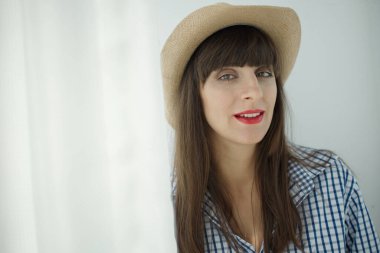 Şapkalı ve kareli gömlekli gülümseyen kadın portresi.