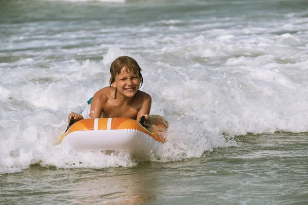 Glücklich mit dem Leben, Porträt des kaukasisch gebräunten Jungen, der auf der Welle auf dem Bodyboard Richtung Ufer rollt — Stockfoto