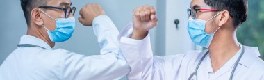 Dirsek çarpması. Coronavirus 'un yayılmasını önlemek için yeni bir roman. İki doktor arkadaş hastanede çıplak elle buluşuyor. Onun yerine dirseklerini çarpıyorlar. Yeni normal başlık arkaplanı