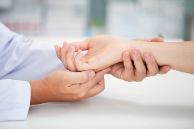 Bilek kemiği sorunu olan Asyalı bir doktor dizüstü bilgisayardaki uzun çalışmanın yol açtığı bilek ağrısı nedeniyle muayene ediliyor. Karpal tünel sendromu, artrit, nörolojik hastalık konsepti. Elin uyuşması.