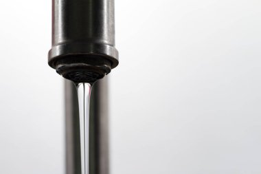 Beyaz arkaplanda bir musluğun minimalist görüntüsünü kapat