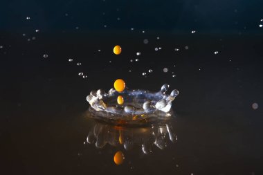 Suya düşen kahve damlaları mavi arka planda, yüksek hızda.