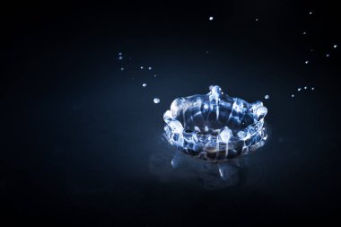 Suya düşen su damlaları mavi arka planda, yüksek hızda