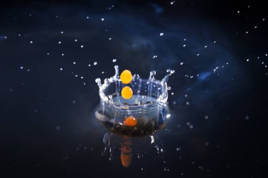 Suya düşen kahve damlaları mavi arka planda, yüksek hızda.