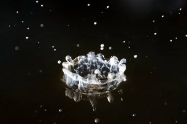 Suya düşen su damlaları mavi arka planda, yüksek hızda