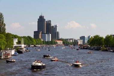 Hollanda 'da Amsterdam' da teknelerle Amstel nehrinin üzerinde güzel bir şehir manzarası.