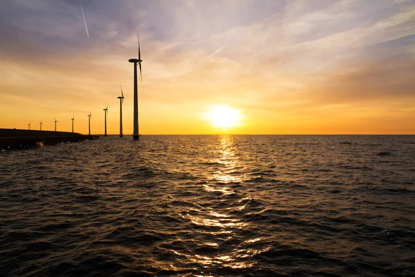 Beautiful landscape view at the Markermeer lake with multiple modern windmills turbines for green sustainable energy in the Netherlands at sunset