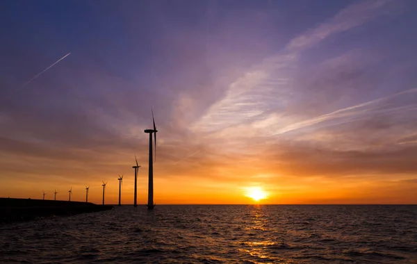 Beautiful landscape view at the Markermeer lake with multiple modern windmills turbines for green sustainable energy in the Netherlands at sunset