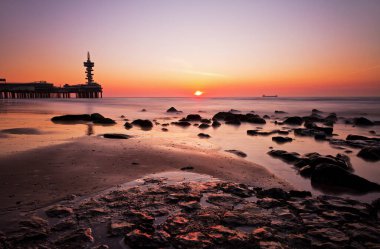 İçinde belgili tanımlık geçmiş ünlü Pier ile Hollanda Scheveningen Plajı, güzel gün batımı