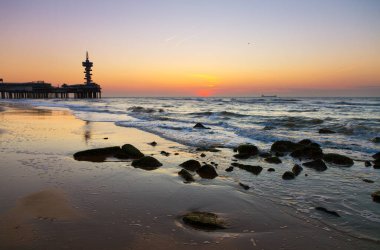 İçinde belgili tanımlık geçmiş ünlü Pier ile Hollanda Scheveningen Plajı, güzel gün batımı