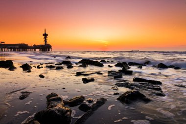 İçinde belgili tanımlık geçmiş ünlü Pier ile Hollanda Scheveningen Plajı, güzel gün batımı