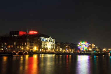 AMSTERDAM, NETHERLANDS - 30 Haziran 2014: Amsterdam, Hollanda 'daki Amstel nehrindeki tiyatronun güzel manzarası, bulutlu güneşli bir yaz günü, 30 Haziran 2014