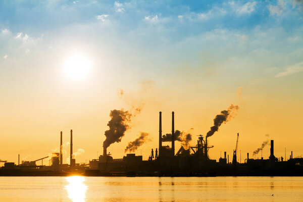Sunset view of the heavy industry with smoking chimneys in IJmuiden, the Netherlands