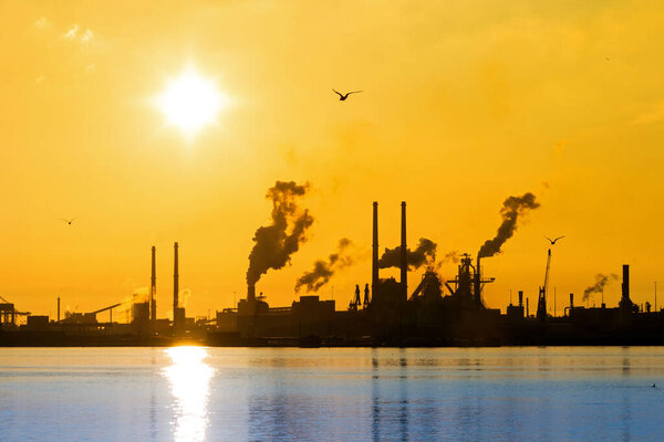 Sunset view of the heavy industry with smoking chimneys in IJmuiden, the Netherlands