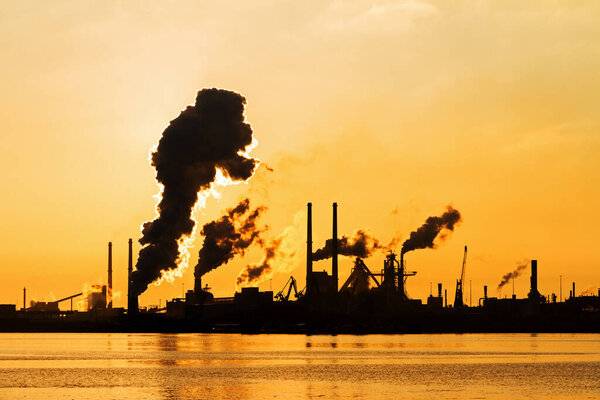 Sunset view of the heavy industry with smoking chimneys in IJmuiden, the Netherlands